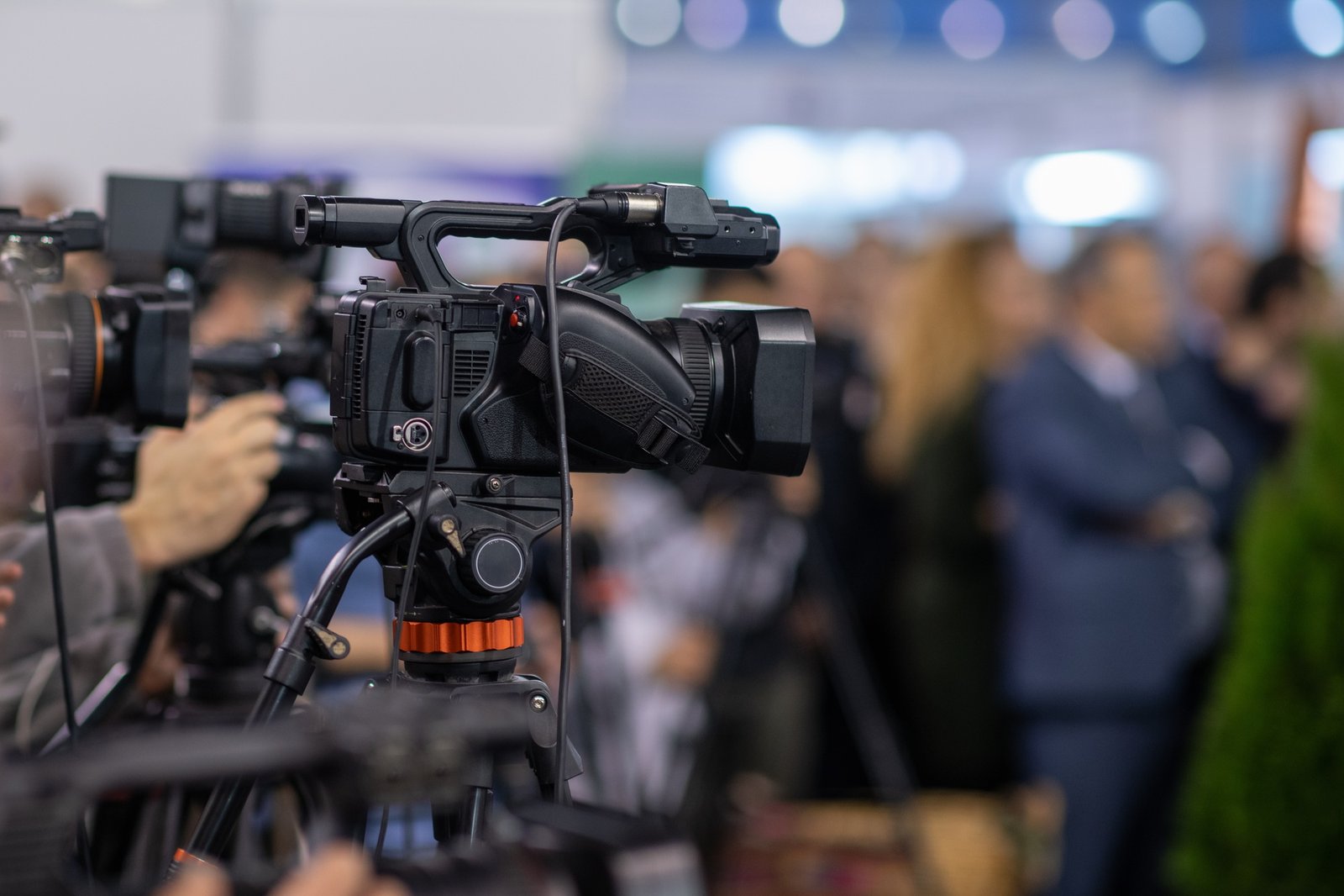 A camera lens captures the essence of a press conference, highlighting media coverage and journalism